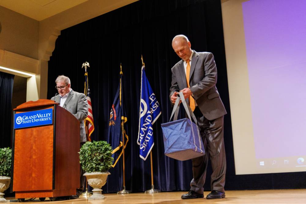 Dr. Len O'Kelly speaking at the podium and Dr. Jeffrey Potteiger holding the People's Choice Winner swag bag.